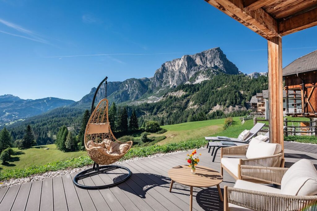 Sonnige Terrasse am Hof mit Hängesessel und altem Wagenrad