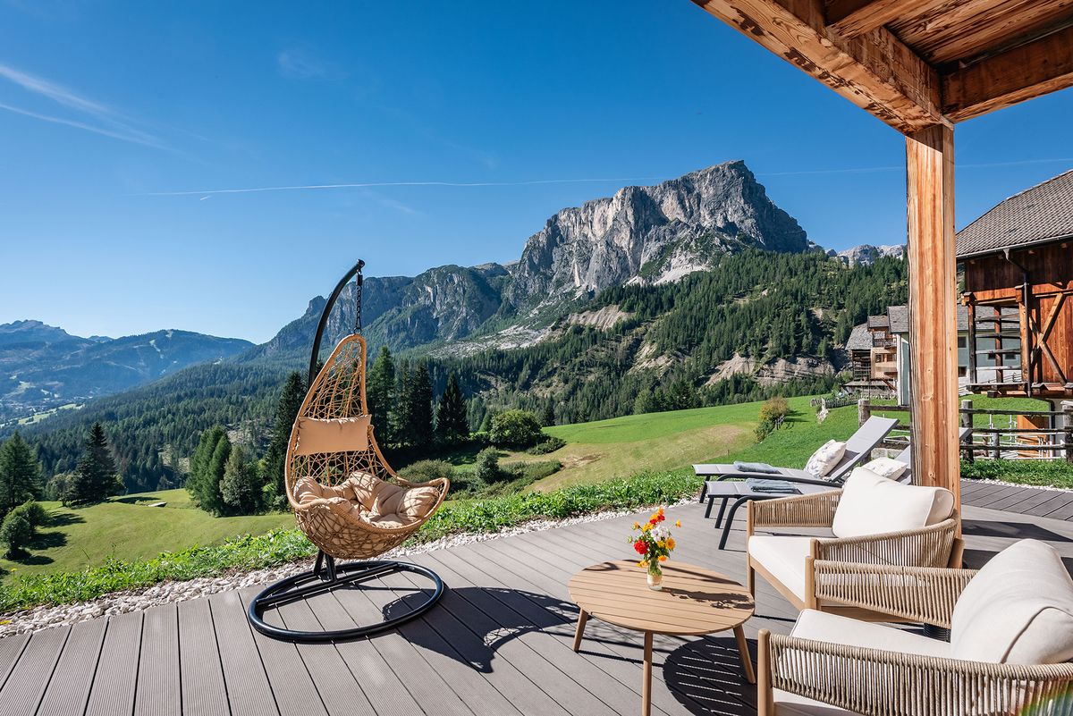 Sonnige Terrasse am Hof mit Hängesessel und altem Wagenrad