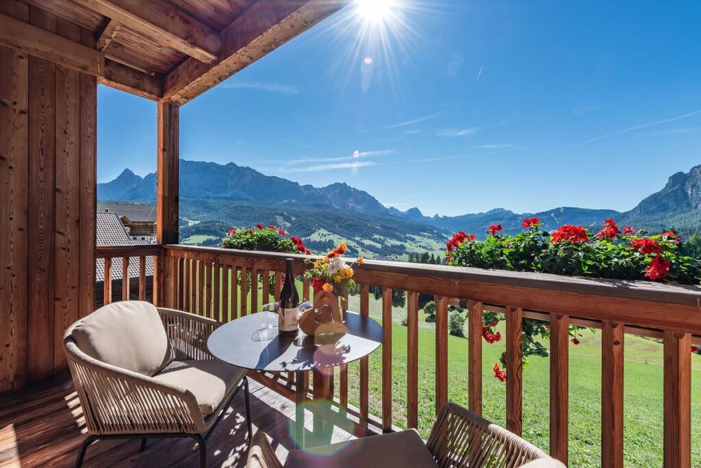 Balkon einer Ferienwohnung mit Geranien und Blick auf die Berge von Alta Badia
