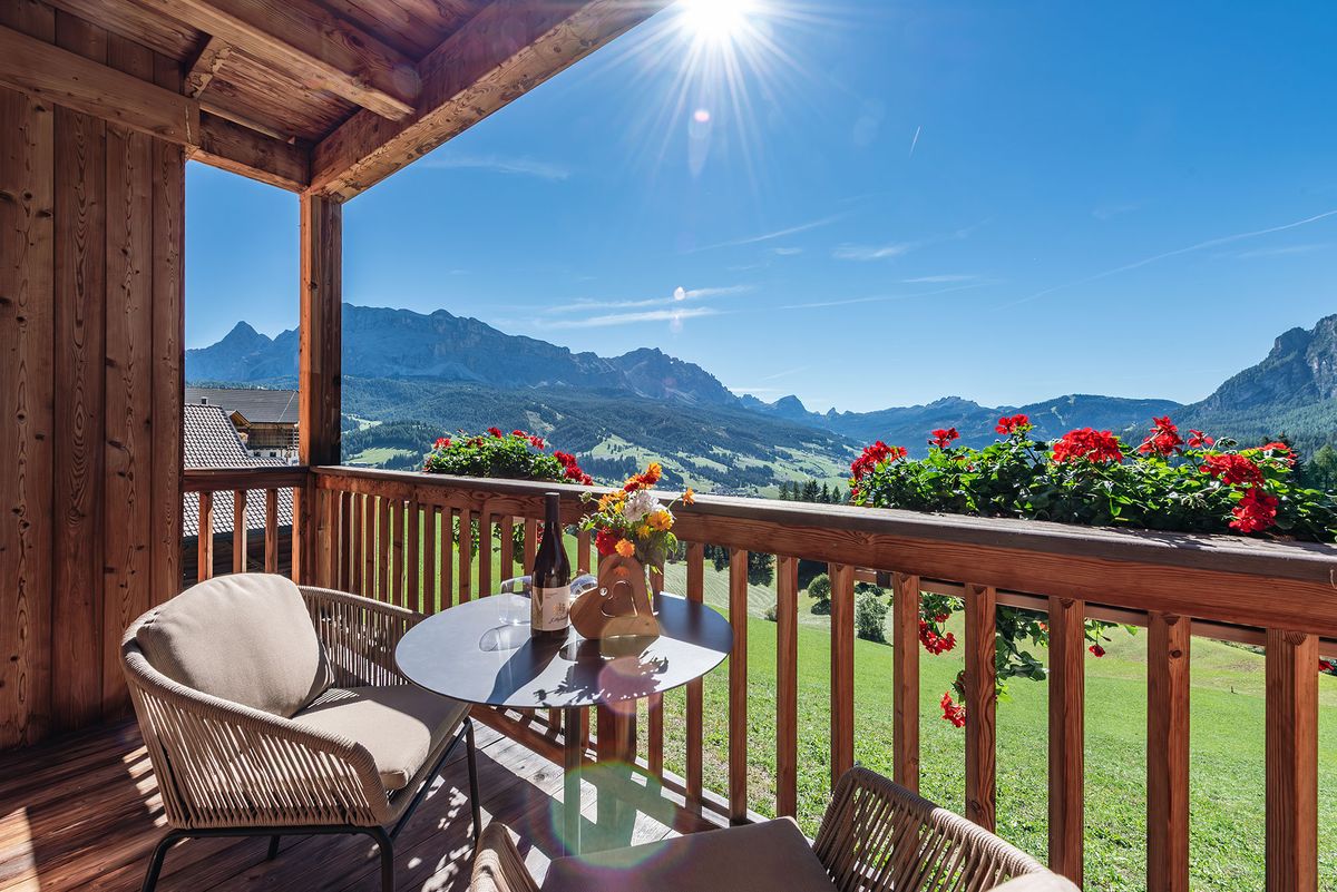 Balkon einer Ferienwohnung mit Geranien und Blick auf die Berge von Alta Badia